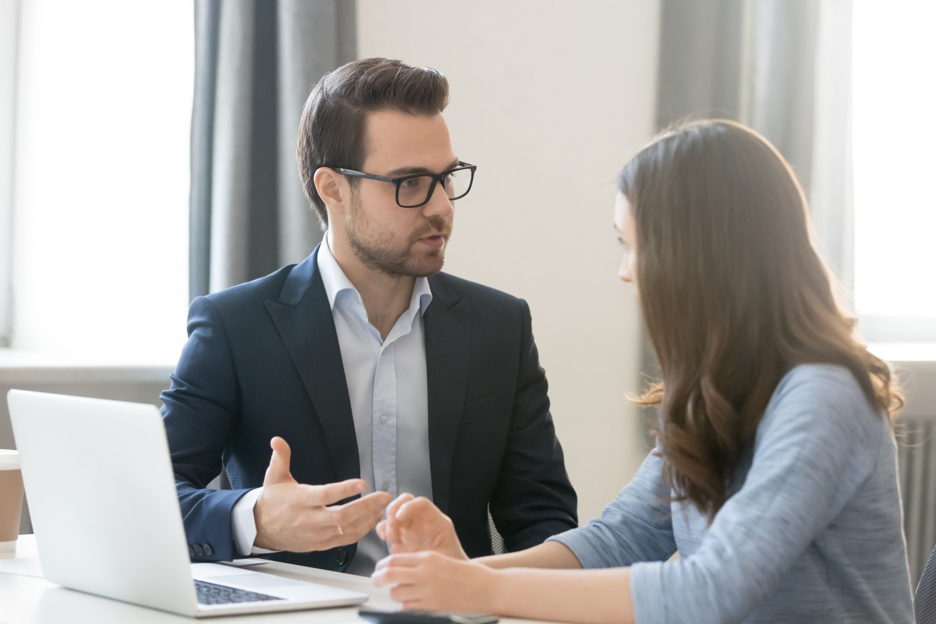 Confident businessman in glasses consulting client, teaching intern
